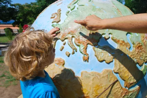 Petit garçon qui montre un point sur un globe 