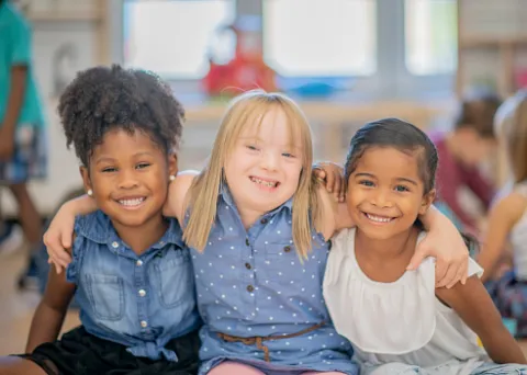 Accolade entre trois petites filles dont une en situation de handicap